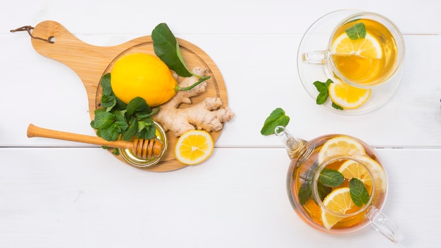 Tetera de vidrio y taza con té, menta y limón. Ingredientes del té