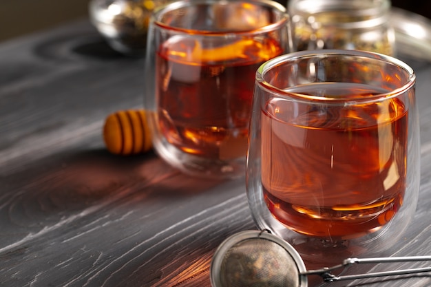 Tetera de vidrio y tazas de té de frutas sobre fondo de madera