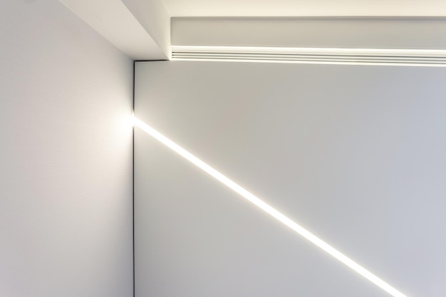 Teto suspenso com lâmpadas de halogênio e construção de drywall em sala vazia em apartamento ou casa Teto estendido branco e forma complexa
