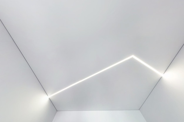 Teto suspenso com lâmpadas de halogênio e construção de drywall em sala vazia em apartamento ou casa Teto estendido branco e forma complexa