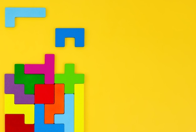 Tetris de madeira multicolorida em um lugar de vista superior de fundo amarelo para texto