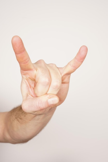 Teufelshörner schließen herauf weiße männliche Hand auf lokalisiertem weißem Hintergrund. Schild aus schwerem Metall.