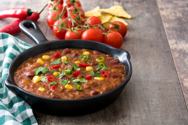 Tex mex mexicano tradicional chili con carne en una sartén en el espacio de copia de mesa de madera