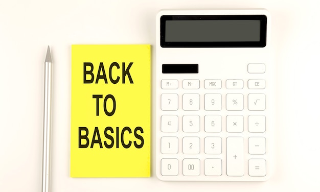 Text Back to Basics auf gelbem Aufkleber neben einem Stift und Taschenrechner