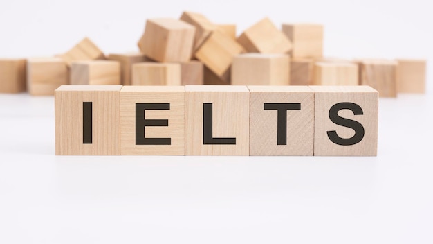 Text IELTS aus Holzwürfeln und verschiedenen Wörtern auf weißem Hintergrund Konzept des Englischlernens