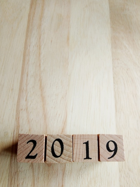 Text-neues Jahr-Karten-Schablone 2019 auf hölzernen Würfeln auf hölzernem Hintergrund