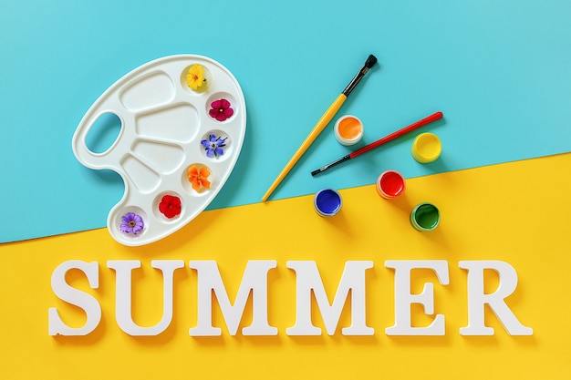 Text Sommer, leuchtend bunte Blumen auf Künstlerpalette, Pinsel und Gouache auf blaugelbem Hintergrund. Kreatives Konzept Sommerfarben malen. Ansicht von oben Flache Lay-Vorlage für Design-Postkarten-Einladung.