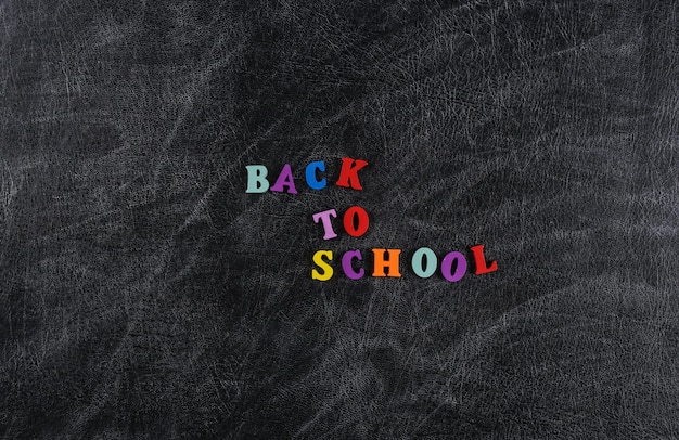 Text zurück zur Schule aus farbigen Buchstaben auf einem Kreidetafelhintergrund.