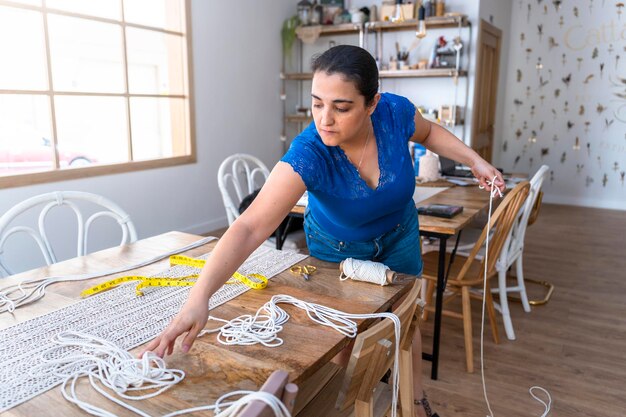 Textilhandwerkliche Frau mittleren Alters bastelt komplizierte Makramee-Designs