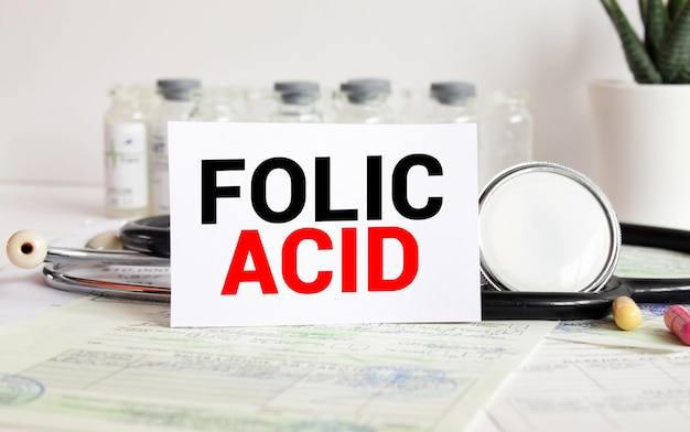 Texto de ácido fólico escrito en una tarjeta en una mesa de madera con fondo médico