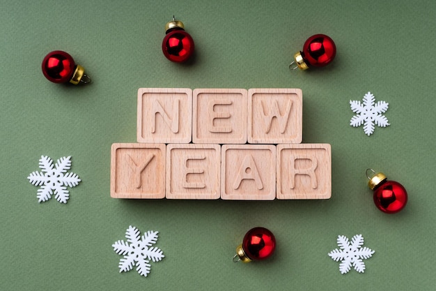 Texto Año Nuevo hecho de cubos de madera sobre un papel de fondo rojo verde brillante primer plano vista superior plano Fondo de Navidad para postal Diseño de Navidad Feliz Año Nuevo