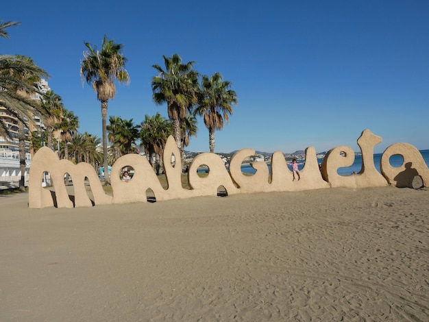 Foto texto en la arena en la playa contra un cielo azul claro