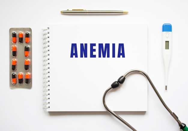 Texto de anemia escrito em um caderno sobre uma mesa e um estetoscópio