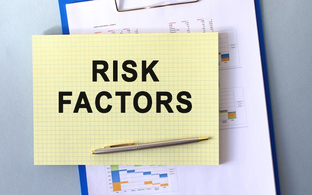 Texto de fatores de risco escrito no bloco de notas com lápis. bloco de notas em uma pasta com diagramas.