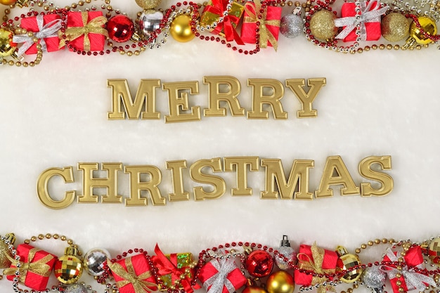 Texto de feliz Natal dourado e decorações de Natal em um fundo branco
