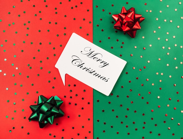 Texto de feliz natalfundo verde e vermelho com brilhos e arcos para presentes lugar do conceito de férias