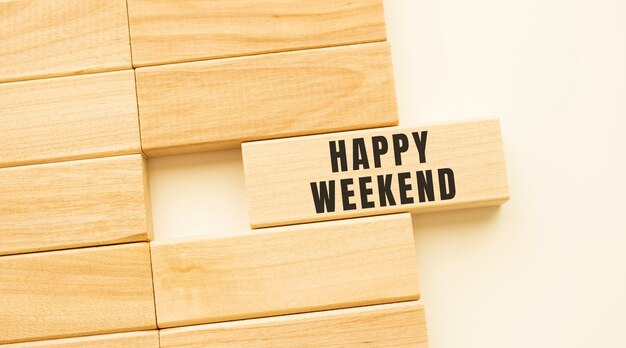 Texto de fim de semana feliz em uma tira de madeira sobre uma mesa branca.