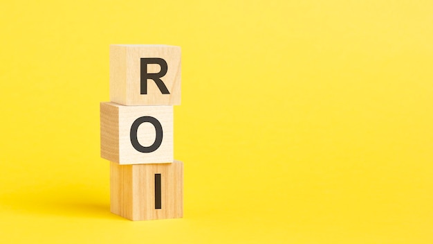 Texto de ROI Return On Investment em bloco de madeira com fundo amarelo