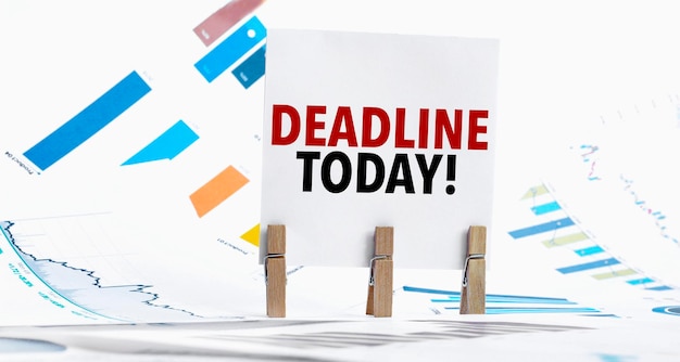 Foto texto deadline today em folha de papel com gráfico, dados, óculos, caneta, portátil e alfinete azul e amarelo em mesa de madeira