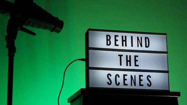 Texto detrás de escena en Lightbox o Cinema Light box. Caja de luz de tablero de película en escalera de estudio y trípode de luz Snoot sobre fondo degradado de colores. Representar detrás de escena el equipo en el que está trabajando.