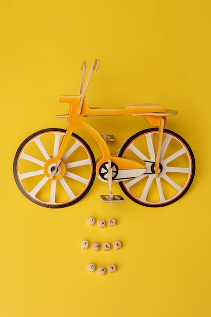 Texto Día sin coches y pequeña bicicleta de juguete sobre fondo amarillo Concepto del día mundial sin coches