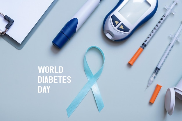 Foto texto del día mundial de la diabetes y suministros médicos de cinta azul y glucómetro en la vista superior de fondo de color