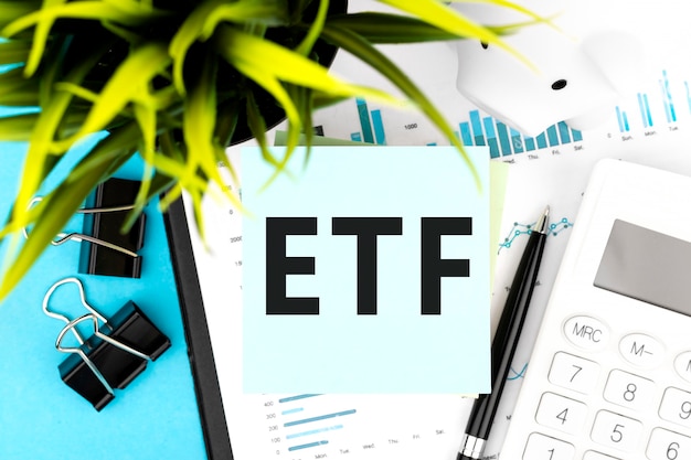 Texto ETF Exchange Traded Fund na etiqueta azul, calculadora, piggy, gráficos. Plano de negócios deitado.