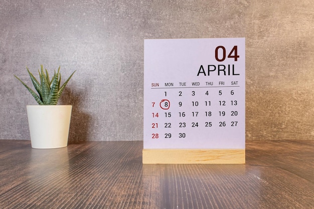 Texto de la fecha del calendario 08 de abril en un bloque de madera blanca con papelería en un escritorio de madera