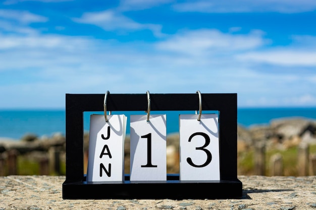 Foto texto de la fecha del calendario del 13 de enero en un marco de madera con un fondo borroso del concepto del calendario oceánico