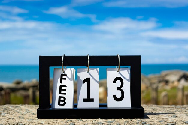 Foto texto de la fecha del calendario del 13 de febrero en marco de madera con fondo borroso del concepto de fecha del calendario oceánico