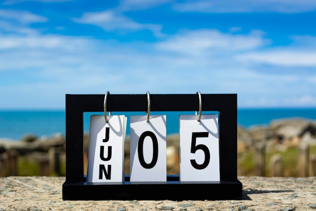 Foto texto de la fecha del calendario de junio en marco de madera con fondo borroso del concepto de fecha del calendario oceánico