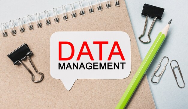 Texto GESTIÓN DE DATOS en una pegatina blanca con superficie de papelería de oficina