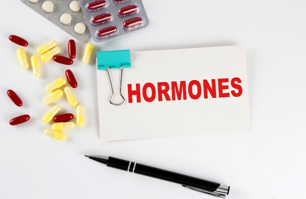 Texto de HORMONAS escrito en una tarjeta con píldoras Concepto médico