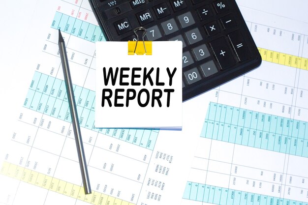 El texto del informe semanal, la calculadora y el bolígrafo están en el escritorio. calculadora y bolígrafo. Concepto de negocio.