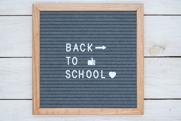 Foto texto en inglés de regreso a la escuela en un tablero de fieltro gris con letras blancas y símbolos como corazón y flecha