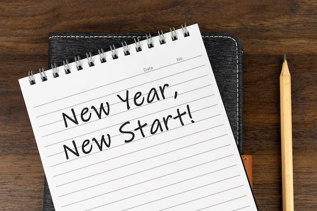 Foto texto de inicio nuevo de año nuevo en el bloc de notas con bolígrafo