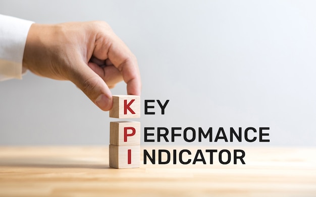 Texto de KPI en caja de madera con mano masculina análisis empresarial.