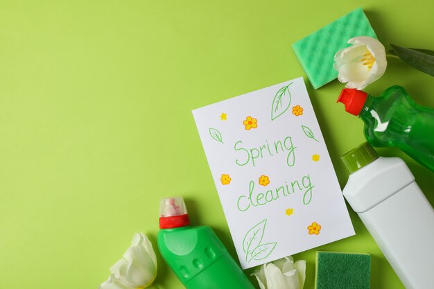 Texto limpieza de primavera, herramientas de limpieza y tulipanes sobre fondo verde