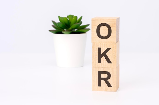 Texto OKR sobre bloques de madera en fondo blanco con espacio de copia