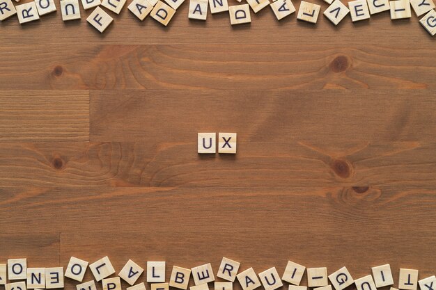 El texto de la palabra "UX" (experiencia del usuario) se escribió con letras de madera aisladas en el escritorio de oficina de madera.