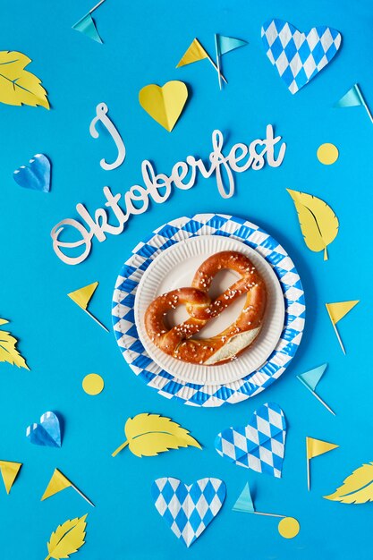 Texto en papel "Me encanta el Oktoberfest", pretzel y decoraciones a juego en papel azul