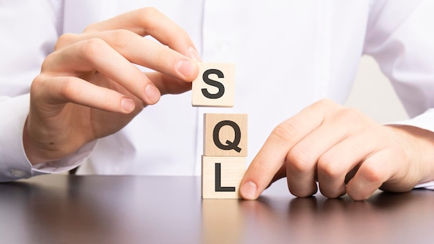 Texto principal calificado para ventas de SQL en bloques cúbicos en manos de un hombre de negocios con camisa blanca