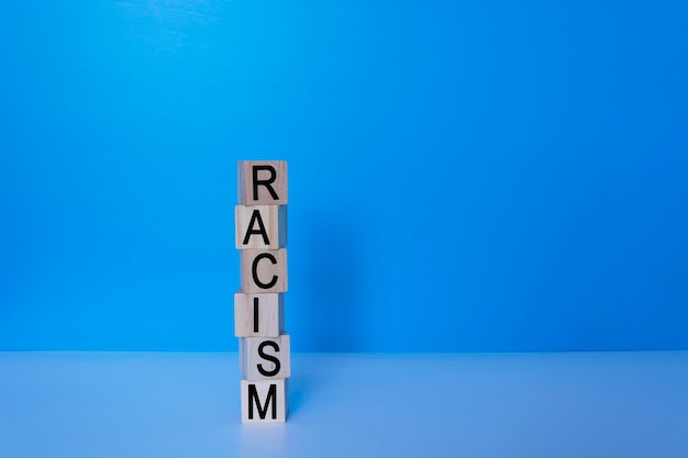 Texto de racismo en bloque de madera con fondo azul.