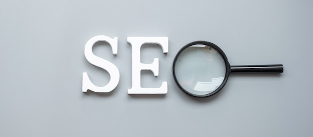 Texto de SEO (Search Engine Optimization) y lupa en gris. Concepto de idea, visión, estrategia, análisis, palabra clave y contenido