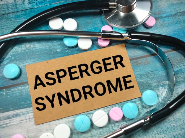 Texto síndrome de asperger em um fundo azul de madeira perto de um estetoscópio e pílulas conceito médico