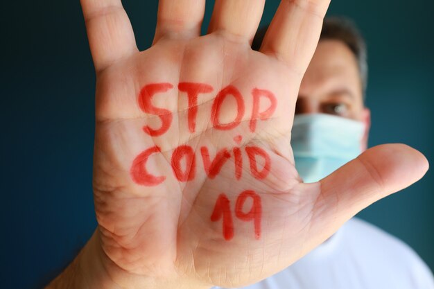 Texto Stop Covid-19 en mano de hombre, hombre europeo advirtiendo sobre coronavirus