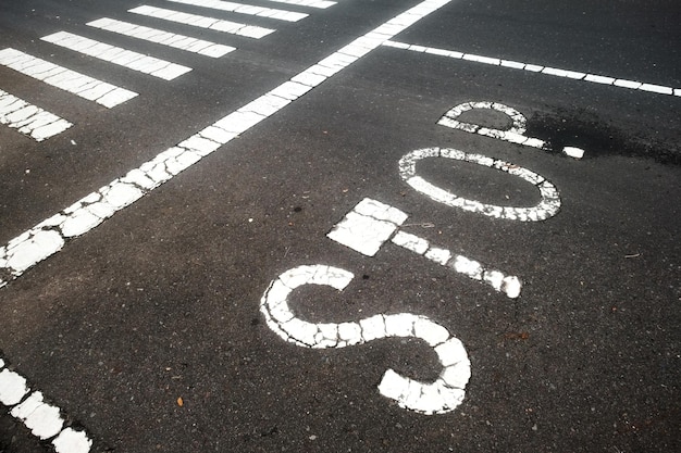 El texto STOP está pintado en el asfalto cerca del paso de peatones