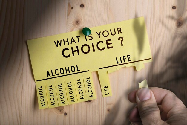 El texto de su elección clavado en un tablón de anuncios de madera. Elección de concepto entre alcohol y vida