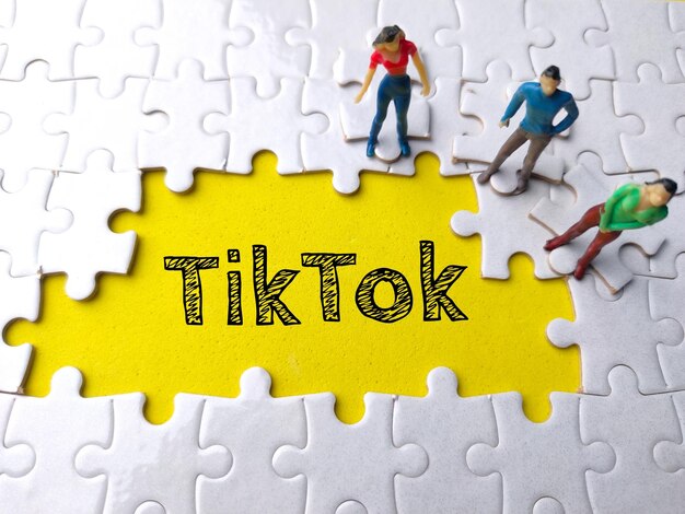 Texto tiktok escrito em fundo amarelo com quebra-cabeça branco e pessoas em miniatura