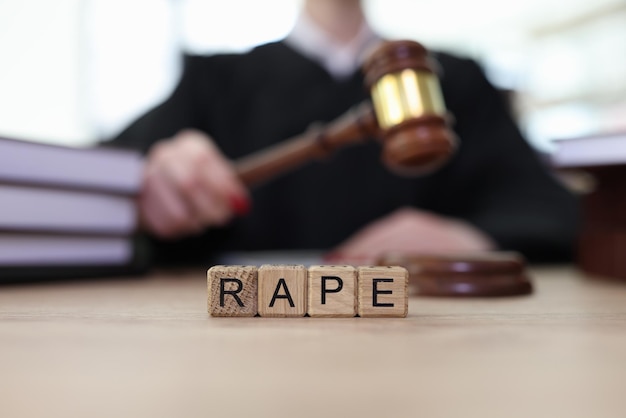 Texto de violación en cubos de madera y juez con martillo en la sala de justicia para víctimas de abuso sexual